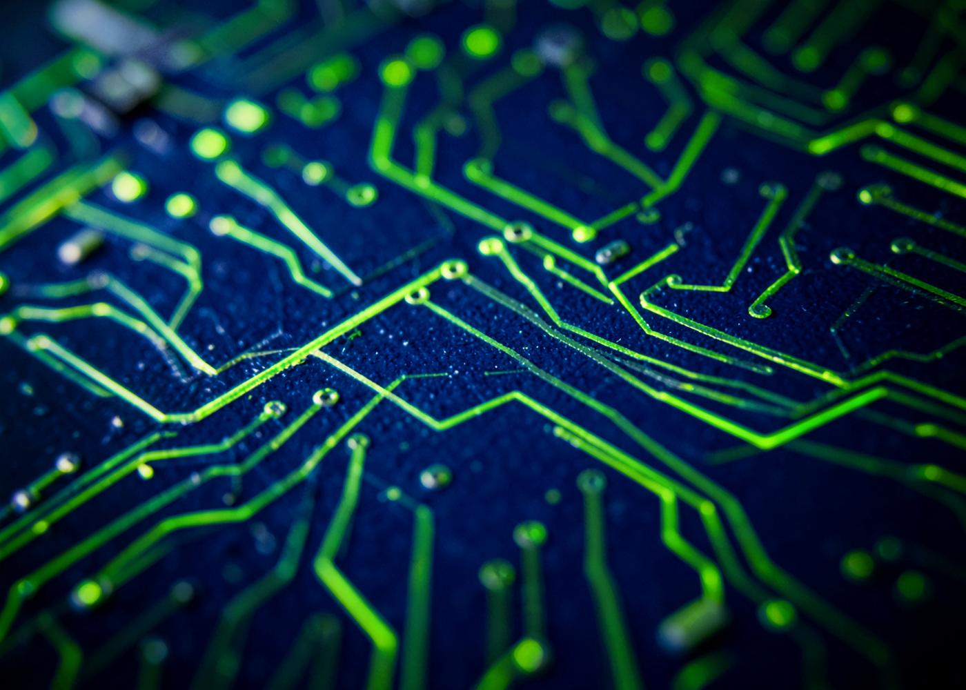 Macro view of a dark blue circuit board with glowing lime traces
