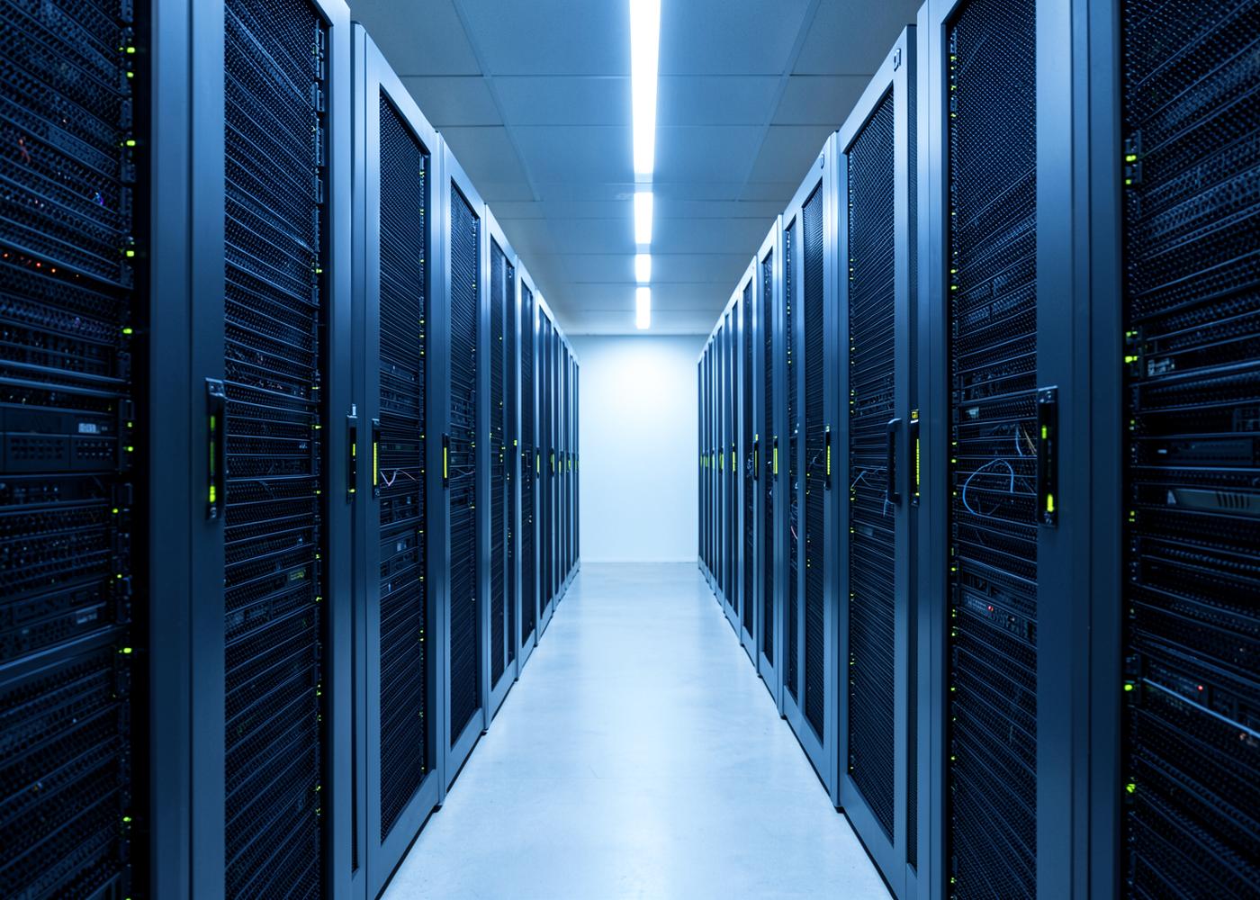Corridor of server racks lit in cool blue with small green status lights, illustrative data centre